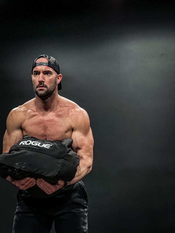 Muscular man lifting Rogue sandbag for workout